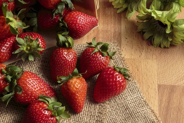 Ahşap kutu ve çuval üzerinde kırmızı çilek yığını