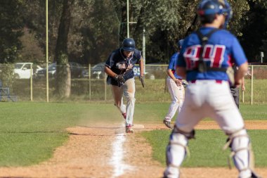 Zagreb. Hırvatistan - 12 Ekim 2014: Beyzbol kulübü Zagreb 'de mavi forma, Olimpija' da ise koyu mavi forma giydi. Tanımlanamayan beyzbol oyuncusu ana sahada koşuyor.