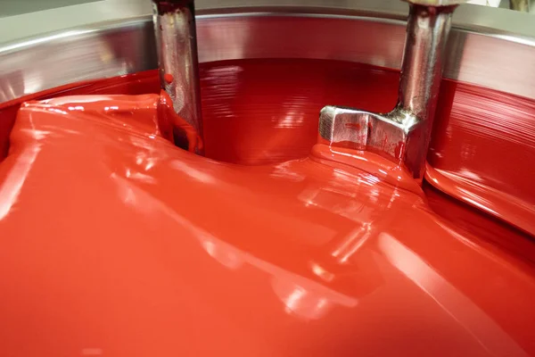 ZAGREB, CROATIA - SEPTEMBER 16, 2014: Cauldron for mixing colors in printing house. Red color in cauldron is Pantone 185 very common as fifth color in printing press