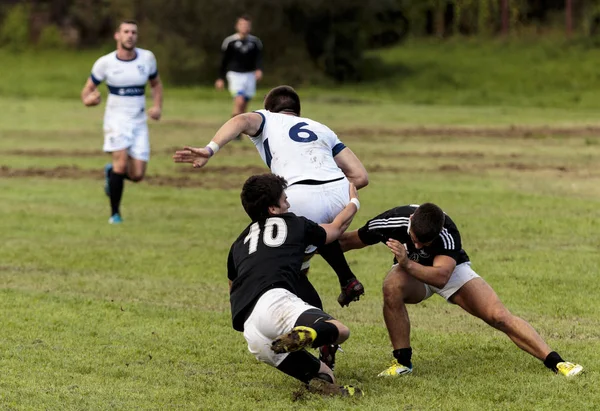 ZAGREB, CROATIA - SEPTEMBER 13, 2014: ZAGREB, CROATIA - SEPTEMBER 13, 2014: Rugby match Rugby Club Zagreb in white jersey and Rugby Club Sinj in black jersey. Unidentified player's tackle each other