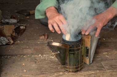 İnsanlar duman ile arılar fumigating için cihaz kindle.
