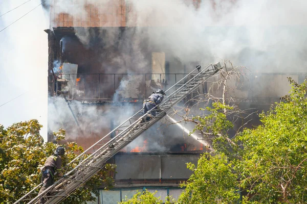 firefighters extinguish a fire in a high-rise residential buildi