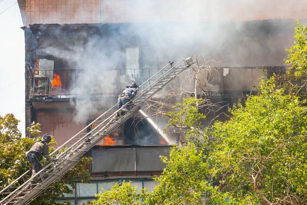 firefighters extinguish a fire in a high-rise residential buildi