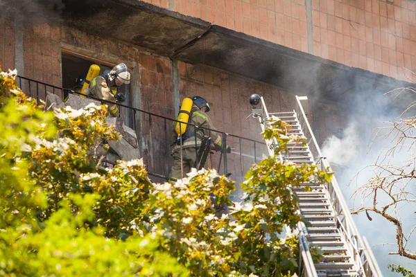 firefighters extinguish a fire in a high-rise residential buildi