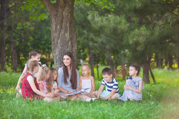 children hold a lesson with the teacher in the park on a green l