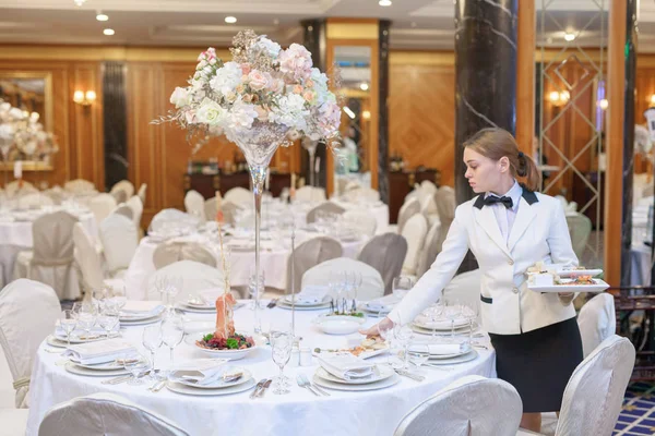 Waiters set the tables in the restaurant for the banquet