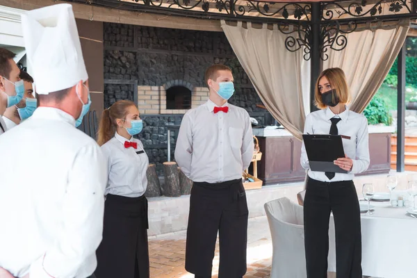 a team of waiters conduct a briefing on the summer terrace of the restaurant