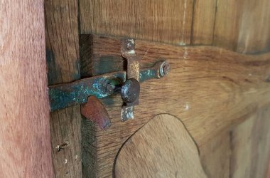 Bu resim, ahşap kapıyı kapalı tutmak için mükemmel çalışan paslı eski bir mandalı tasvir ediyor. El yapımı ahşap kapı çok sade ve otantik. Metal pranga oldukça paslı ama mükemmel çalışıyor.