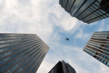 Airplane flying between tall skyscrapers in city skyline