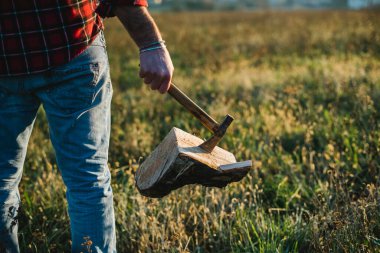 axe embedded in firewood held by man in jeans