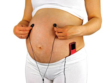 Beyaz giyinmiş, beyaz arka plan üzerinde bir kadın, embriyo ile birlikte rahatlatıcı müzik dinler.