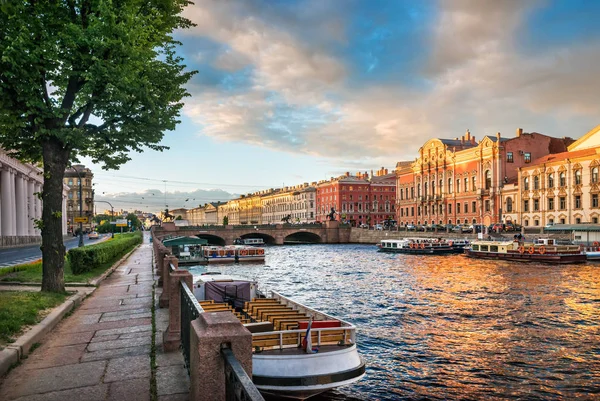 河小船旅行在 Fontanka 河在圣彼得堡在一个夏天晴朗的晚上和阿尼奇科夫桥梁在距离 — 图库照片