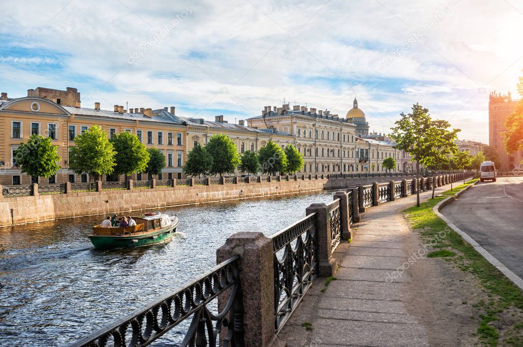 The boat sails along the Moika River in St. Petersburg towards the St. Isaac's Cathedral in the early summer sunny morning