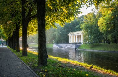 Rossi Pavilion sabah güneşi ve yanan sokak ağaçları ışınlarının St Petersburg Moika Nehri kıyısında