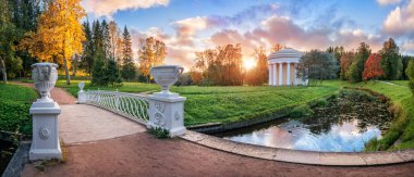 The Temple of Friendship on the bank of the Slavyanka River in Pavlovsk and the white vases of the Pig-iron Bridge on an autumn sunny evening clipart
