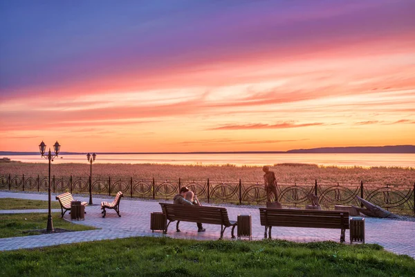 Kostroma地域のGalich湖の上の美しいピンクの夕日と堤防のベンチで恋のカップル — ストック写真