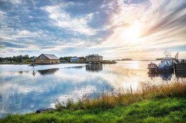 Solovetsky Adaları 'ndaki Refah Körfezi' ndeki gemiler ve gökteki sonbahar güneşi. Gemi adı: Pechak
