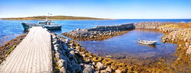 Taştan bir körfezde küçük bir tekne ve Zayatsky Adaları 'ndaki ahşap bir iskelede büyük bir gemi. Yazıt: Aziz Nicholas