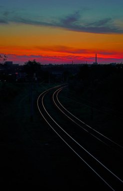 Demiryolu kırmızı gün batımı bir arka plan üzerinde mesafe içine bırakarak
