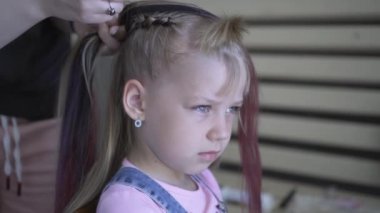 Pigtails genç bir kız örgülü vardır. Kuaförde saç modeli yapıyorum. Saçınızı şekillendirin.