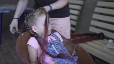 Pigtails genç bir kız örgülü vardır. Kuaförde saç modeli yapıyorum. Saçınızı şekillendirin.