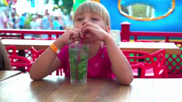 女孩在咖啡馆里用吸管喝莫吉托 看着一杯饮料 在公园里休息 在炎热的日子里解渴 — 图库视频影像
