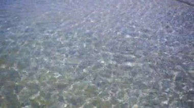 Berrak sakin deniz, sahil şeridi. Küçük dalgalar yavaşça kumlu kıyıya yuvarlanıyor..