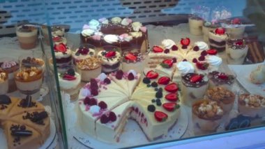 Şekerleme penceresinde lezzetli kek ve eclairs. Karamel, krema, fındık, çilek. Çikolata, hafif krema ile süt.