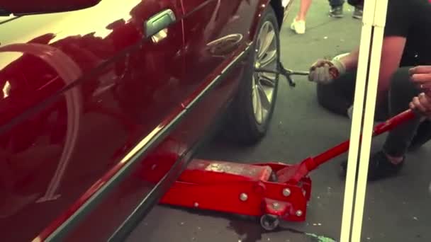 男人在汽车上换一个磨损的轮子 拆下车轮并使用千斤顶 轮胎服务 — 图库视频影像