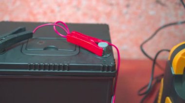 Terminallere sabitlenmiş iki atlayıcılı araba aküsü. Pil Şarj Cihazı. Kış için araç hazırlığı