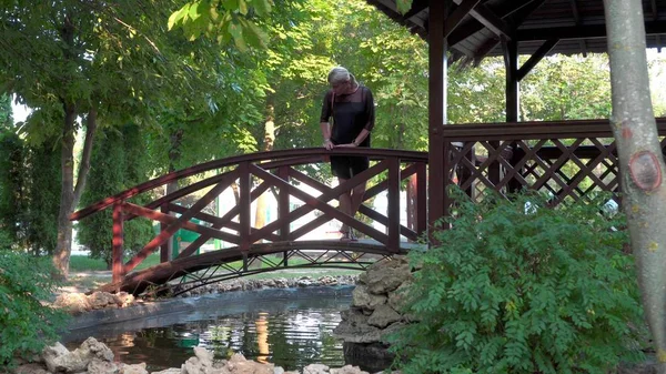 The girl walks alone in the park next to a small pond. Resting-place