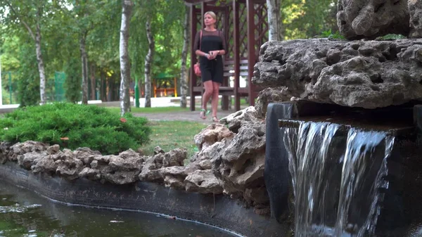 Het meisje loopt alleen in het park naast een kleine vijver. Rustplaats — Stockfoto