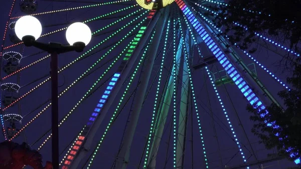 Parc d'attractions en soirée. Lumières multicolores lumineuses d'une roue ferris . — Photo
