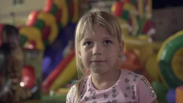 Het gezicht van een klein meisje op de achtergrond van een pretpark. — Stockfoto