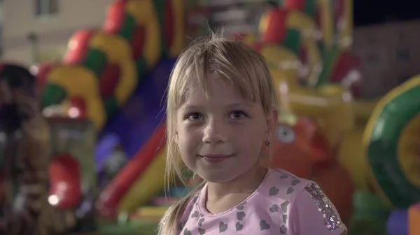Het gezicht van een klein meisje op de achtergrond van een pretpark. — Stockfoto