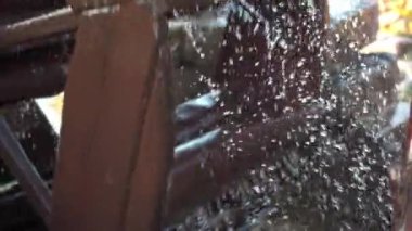 Suyun basıncı eski bir su değirmenini döndürür. Sprey farklı yönlere uçuyor.