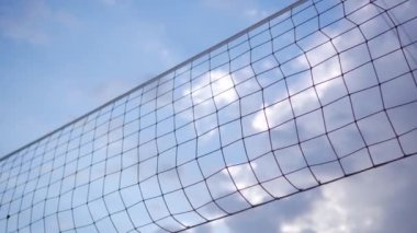 Voleybol ağının dokusu mavi gökyüzünün arka planında bulutlarla birlikte. Kumsalda spor yaparken dinleniyorum..