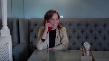 Takım elbiseli genç bir iş kadını elinde akıllı bir telefonla arıyor ve mesajları inceliyor..