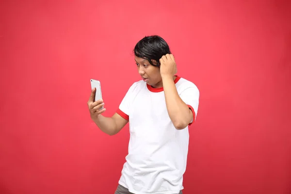 Hombre Indonesio Retrato Mirando Teléfono Inteligente Aislado Sobre Fondo Rojo —  Fotos de Stock