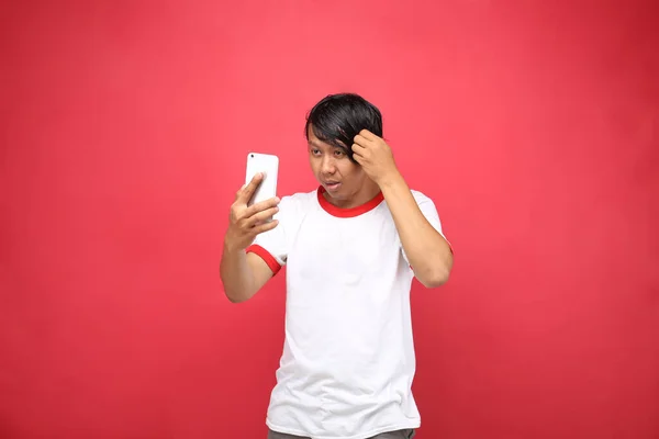 Jóvenes Indonesios Mirando Teléfono Inteligente Aislado Sobre Fondo Rojo — Foto de Stock