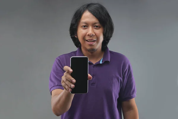 new normal indonesia man pointing smartphone with purple shirt isolated on gray background
