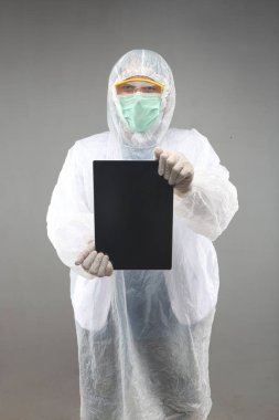 Gri arka planda tablet gösteren tıbbi lateks eldivenler giyen koruyucu koruyucu koruyucu giysili yeni bir Asyalı doktor.