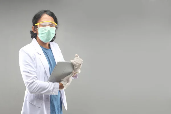 male asian doctor with face mask, gloves, googles holding tablet smartphone for information pandemic covid-2019