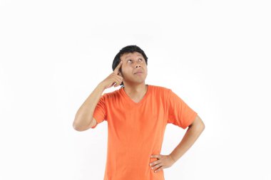 Asia 'nın turuncu tişörtü kullanarak boş bir alanda düşünmesi inanılmaz. Asyalı adam düşüncelerini ifade eder.