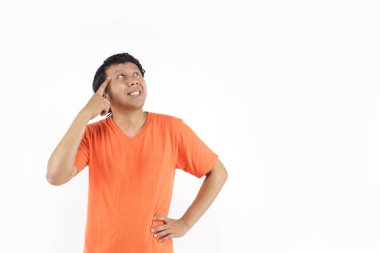 Asyalı adam turuncu tişörtle düşünür ve gülümserdi. Endonezyalı adam turuncu tişört giymeyi düşünüyor.