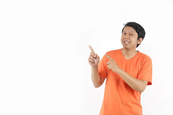 オレンジのTシャツで空白の空間を指差している興奮したアジアの人々 アジア系の男が — ストック写真
