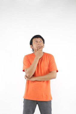 Asyalı adam turuncu tişört giymeyi düşünüyor..