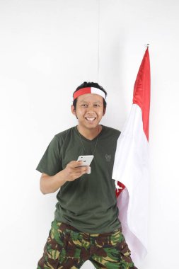 Endonezyalı usta akıllı telefon kullanıyor ve elinde kırmızı beyaz bayrak tutuyor..