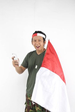 Endonezyalı kahraman akıllı telefon kullanıyor ve elinde kırmızı beyaz bayrak tutuyor..