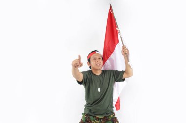 Endonezyalı asker önüne bakıyor ve elinde Endonezya bayrağı sallıyor.